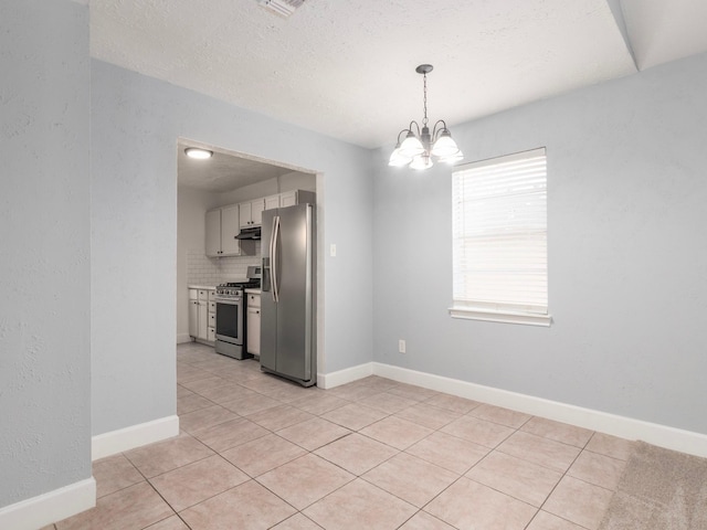 unfurnished dining area featuring an inviting chandelier, a textured ceiling, and light tile patterned flooring