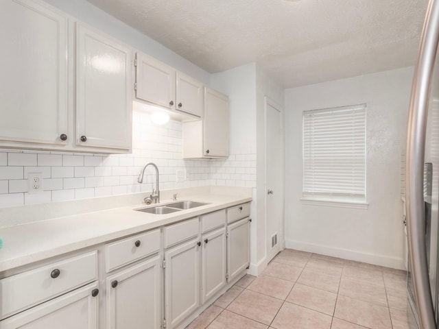 kitchen featuring white cabinetry, sink, light tile patterned floors, and tasteful backsplash