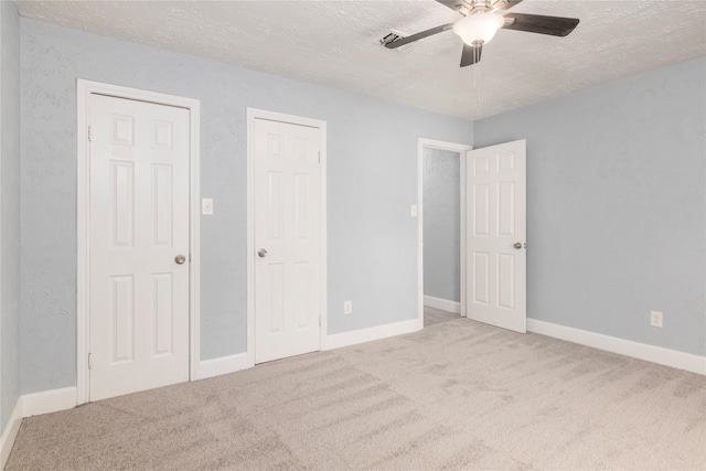 unfurnished bedroom with ceiling fan, light colored carpet, and a textured ceiling