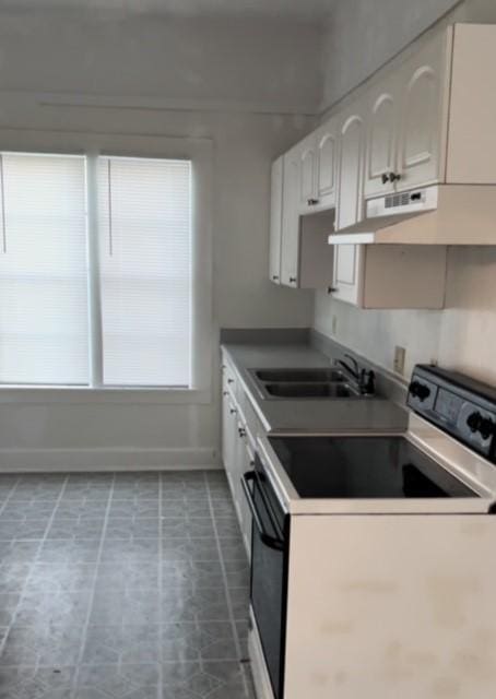 kitchen featuring range with electric cooktop, sink, and white cabinets