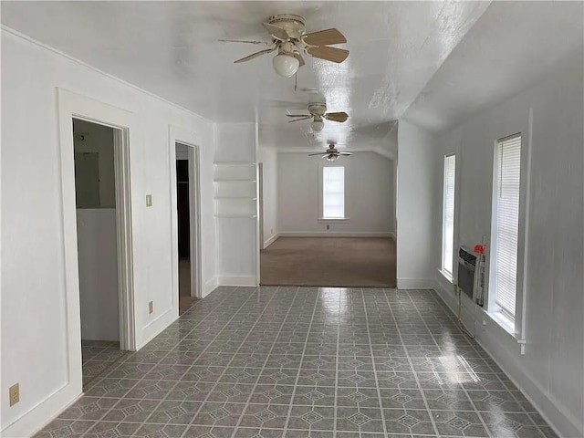 empty room featuring lofted ceiling, ceiling fan, baseboards, and tile patterned floors