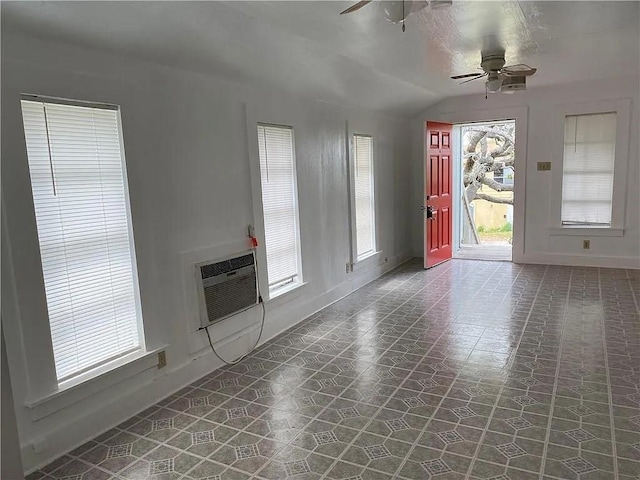 entryway featuring baseboards, lofted ceiling, ceiling fan, tile patterned floors, and a wall mounted air conditioner