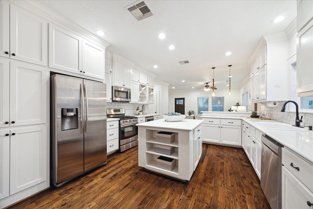 kitchen featuring pendant lighting, sink, stainless steel appliances, a center island, and kitchen peninsula