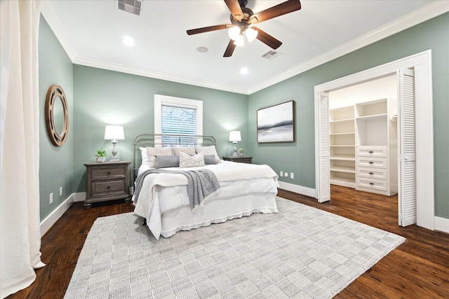 bedroom with ceiling fan, ornamental molding, dark hardwood / wood-style flooring, and a walk in closet