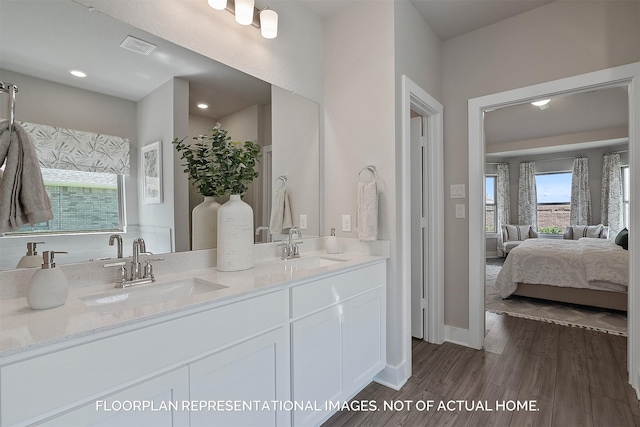 bathroom with double vanity, ensuite bath, a sink, and wood finished floors