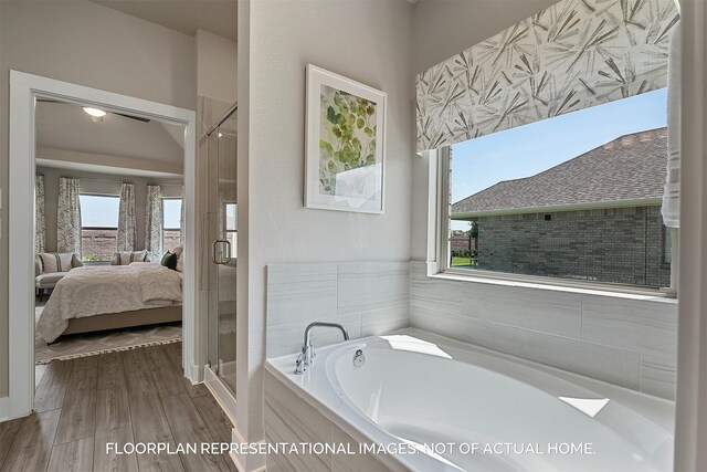 ensuite bathroom with a garden tub, ensuite bath, wood finished floors, and a stall shower