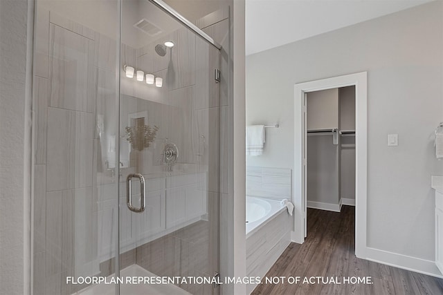 full bath featuring a stall shower, visible vents, wood finished floors, a walk in closet, and a bath