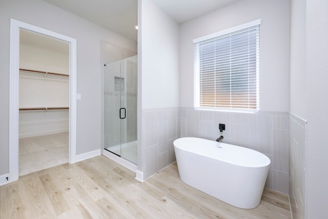 bathroom with shower with separate bathtub, hardwood / wood-style floors, and tile walls