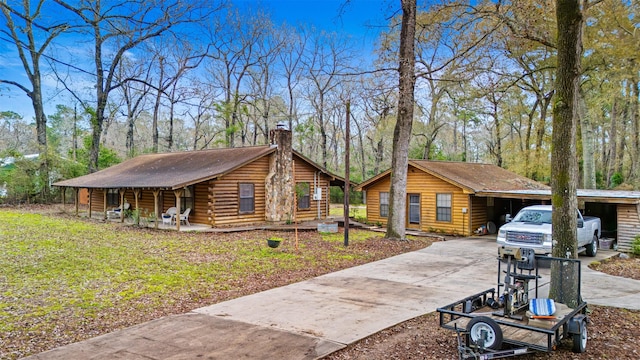 log home featuring a carport and a front lawn