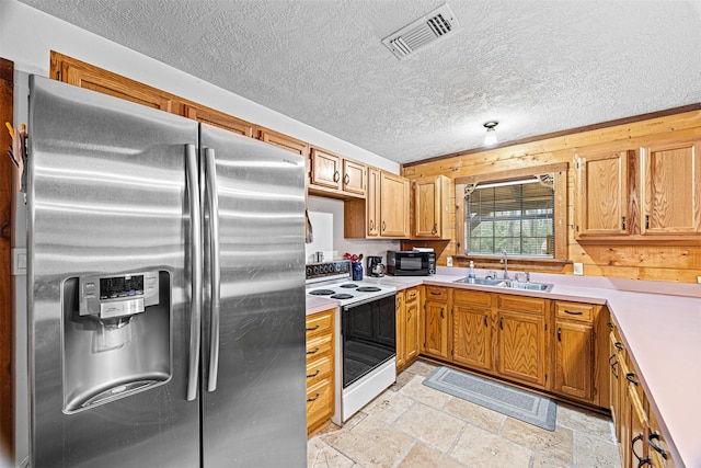 kitchen with stainless steel refrigerator with ice dispenser, sink, electric range, and a textured ceiling