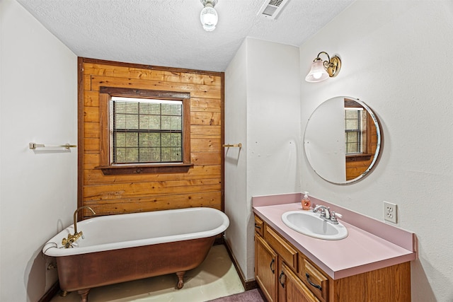 bathroom with vanity, a tub to relax in, a textured ceiling, and wood walls