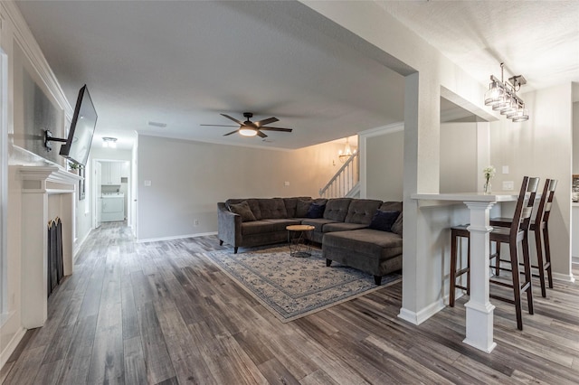 living room featuring hardwood / wood-style flooring, crown molding, washer / dryer, and ceiling fan with notable chandelier