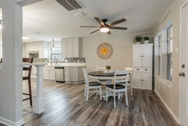 dining room featuring ceiling fan, dark wood-type flooring, sink, and a textured ceiling