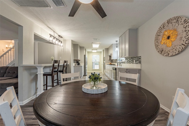 dining area with ceiling fan, dark hardwood / wood-style flooring, sink, and a textured ceiling