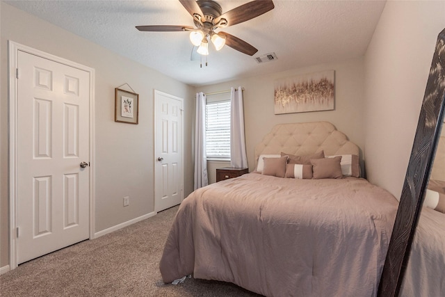 carpeted bedroom featuring ceiling fan and a textured ceiling