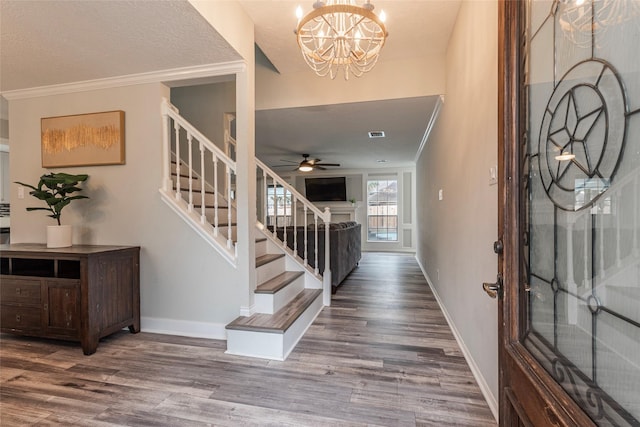 entryway with wood-type flooring, ornamental molding, a chandelier, and a textured ceiling