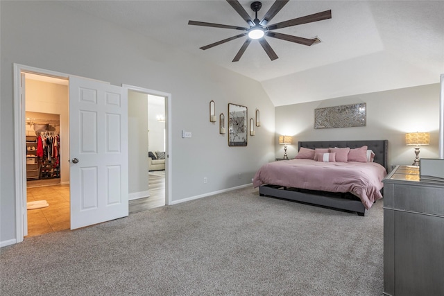 carpeted bedroom featuring a walk in closet, lofted ceiling, and ceiling fan