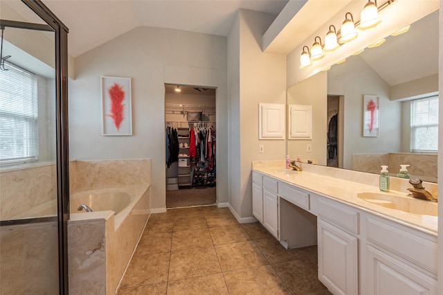 bathroom with lofted ceiling, tile patterned flooring, vanity, and a tub