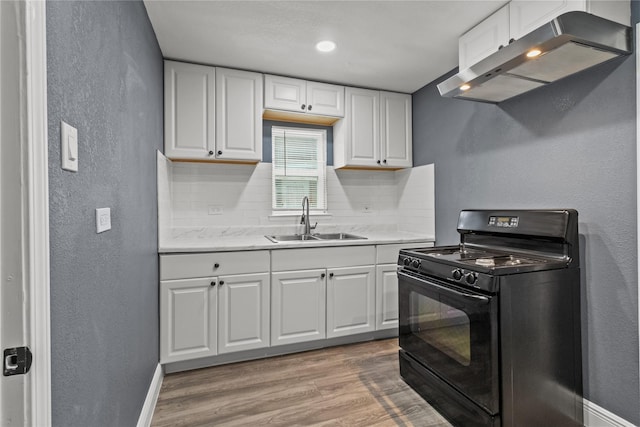 kitchen featuring black stove, ventilation hood, white cabinetry, sink, and light hardwood / wood-style flooring