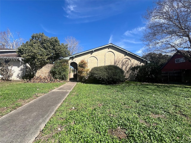 view of front of home with brick siding, a front lawn, and fence