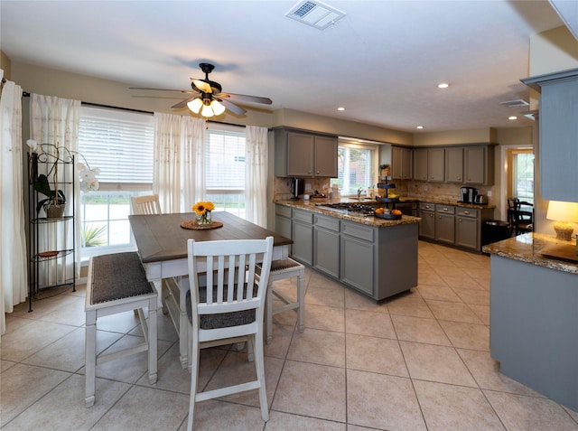 kitchen featuring gray cabinets, light tile patterned floors, and dark stone counters