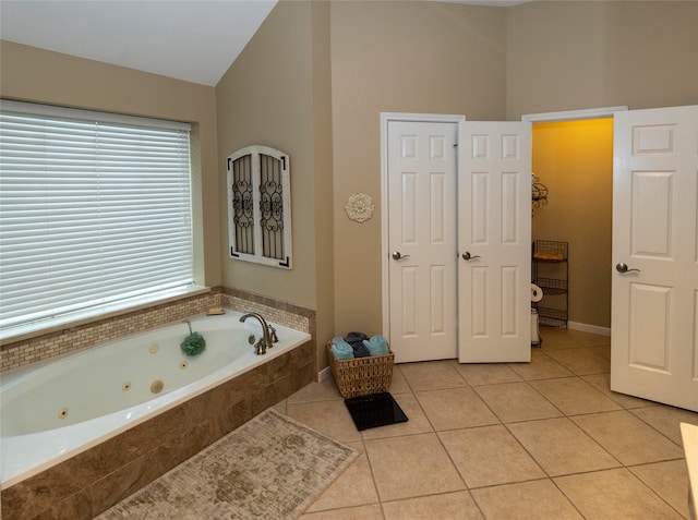 bathroom with lofted ceiling, tile patterned flooring, and tiled tub