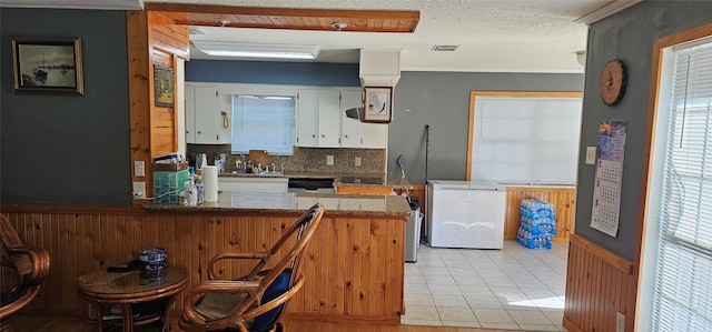 kitchen with fridge, white cabinets, light tile patterned flooring, decorative backsplash, and kitchen peninsula