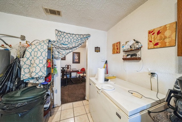 clothes washing area with a textured ceiling and light tile patterned floors