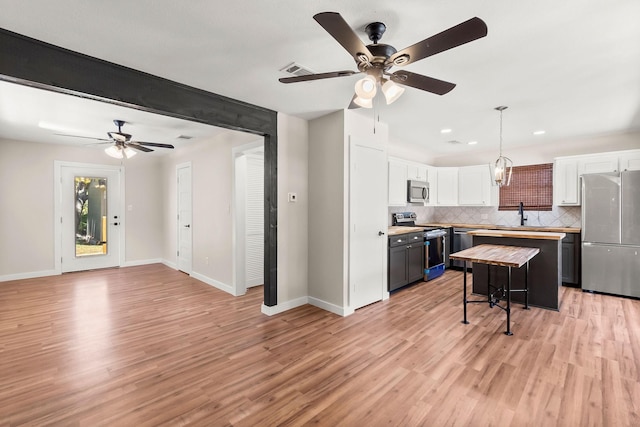 kitchen with appliances with stainless steel finishes, pendant lighting, white cabinetry, wooden counters, and a kitchen breakfast bar