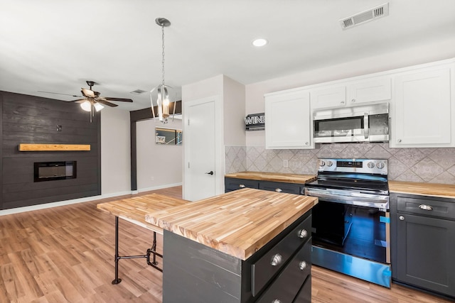 kitchen featuring appliances with stainless steel finishes, a kitchen island, pendant lighting, a fireplace, and white cabinets