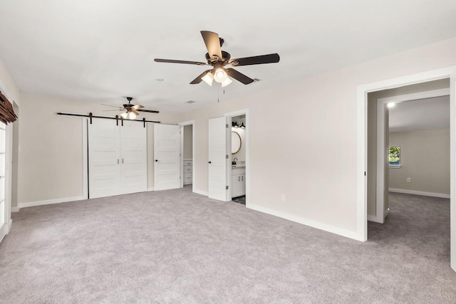 unfurnished bedroom featuring ceiling fan, carpet flooring, and a barn door