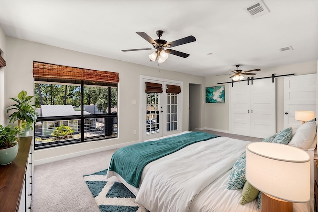 carpeted bedroom featuring a barn door and ceiling fan