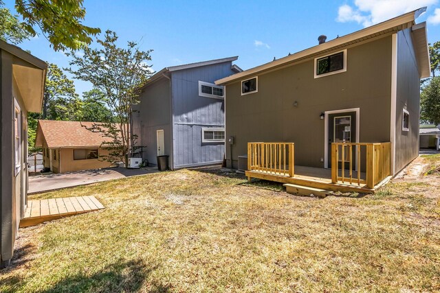 rear view of property featuring a lawn, a patio, and a deck