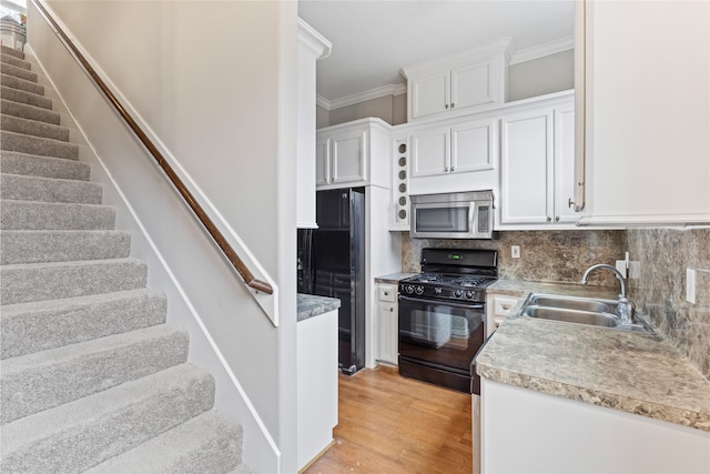 kitchen featuring white cabinetry, sink, ornamental molding, and black appliances