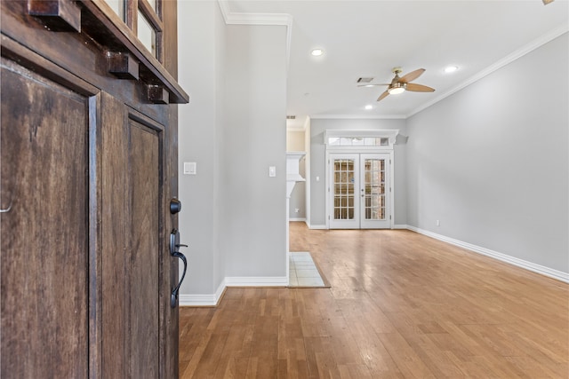 foyer with ornamental molding, wood-type flooring, ceiling fan, and french doors