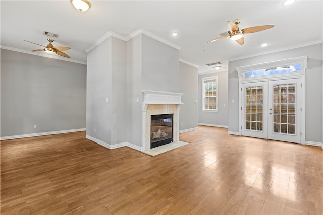 unfurnished living room with a tiled fireplace, ornamental molding, light hardwood / wood-style floors, and ceiling fan