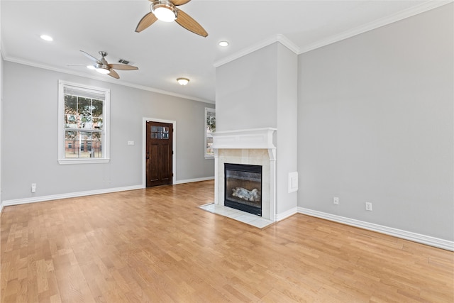 unfurnished living room with a tiled fireplace, crown molding, light hardwood / wood-style floors, and ceiling fan