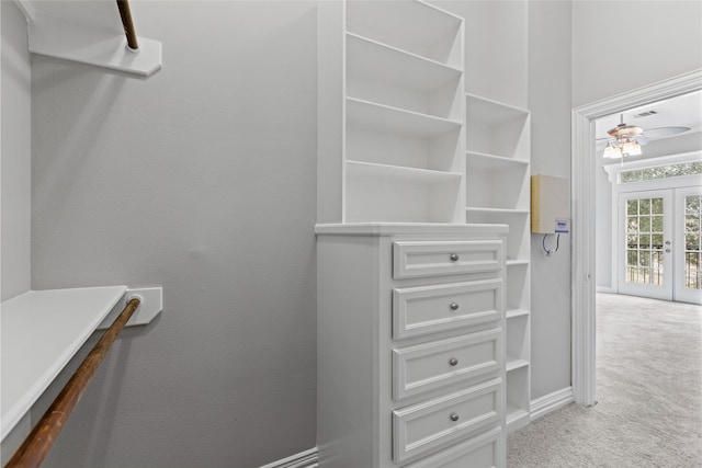 walk in closet featuring french doors, ceiling fan, and light carpet