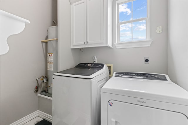 clothes washing area with cabinets, washer and dryer, and gas water heater