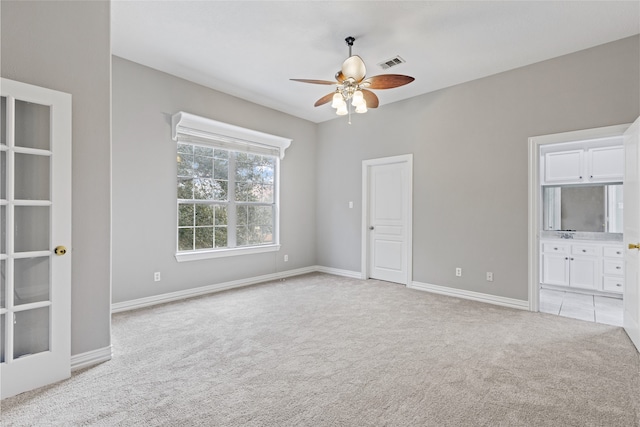 unfurnished bedroom with light colored carpet, ceiling fan, and ensuite bathroom