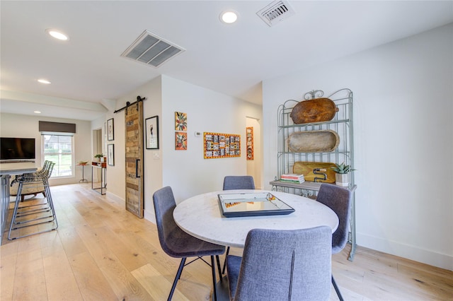 dining area with light hardwood / wood-style floors and a barn door