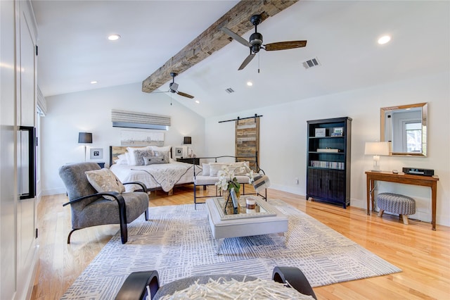 bedroom featuring ceiling fan, a barn door, vaulted ceiling with beams, and light hardwood / wood-style floors