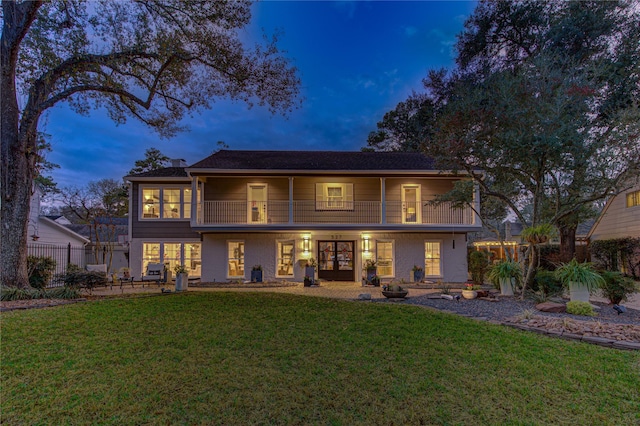 view of front of house featuring a balcony and a yard