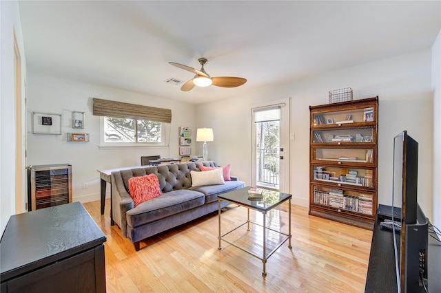 living room featuring wine cooler, light hardwood / wood-style floors, and ceiling fan