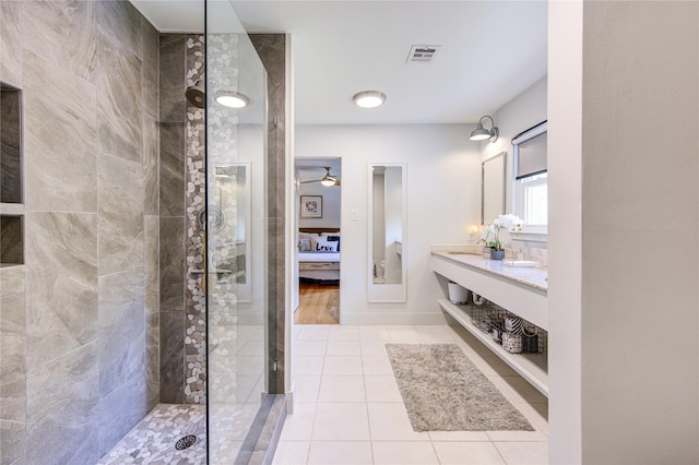 bathroom featuring tile patterned flooring, vanity, and tiled shower