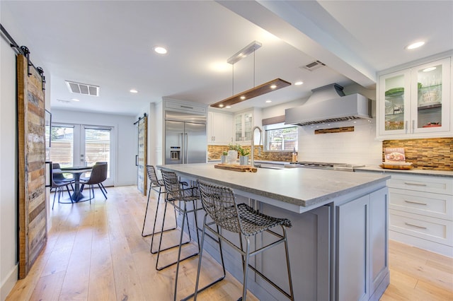 kitchen featuring a center island, a barn door, custom range hood, and white cabinets