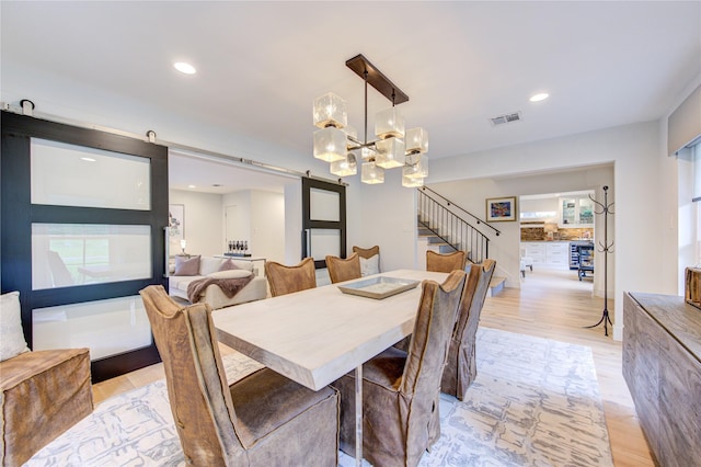 dining space with a barn door and light hardwood / wood-style floors