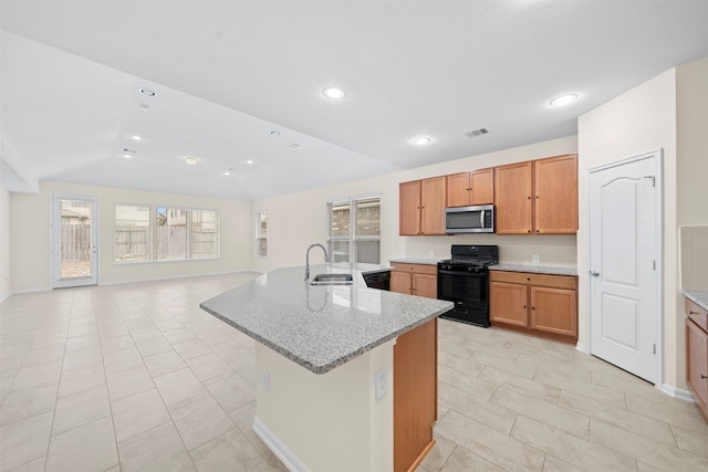 kitchen featuring lofted ceiling, sink, light stone countertops, a kitchen island with sink, and black appliances