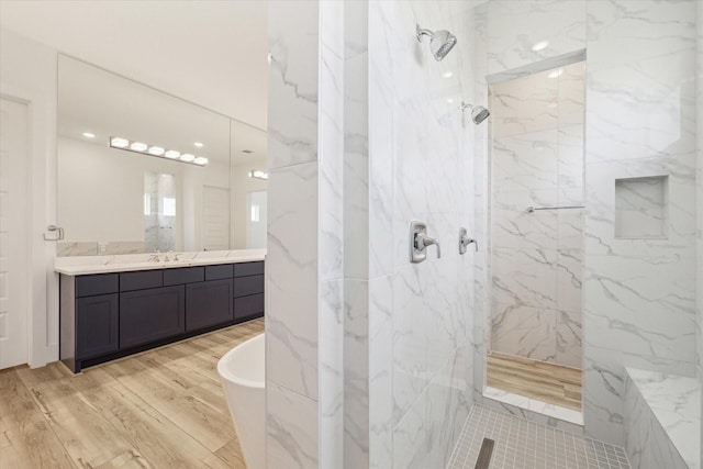 full bathroom with a marble finish shower, a freestanding tub, vanity, and wood finished floors