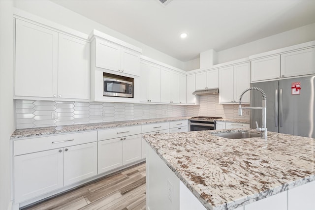 kitchen featuring stainless steel appliances, a kitchen island with sink, sink, and white cabinets